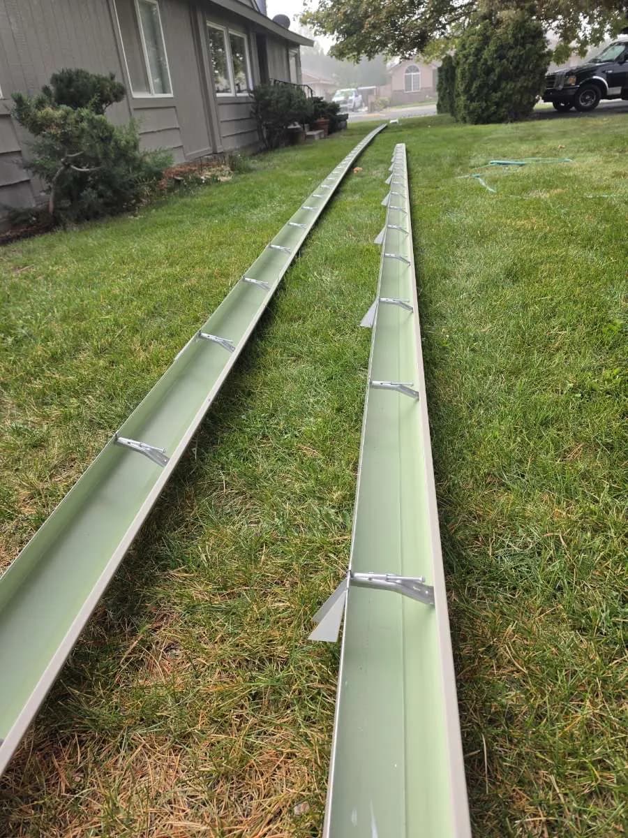 Two fresh gutter runs laid out on the lawn before install